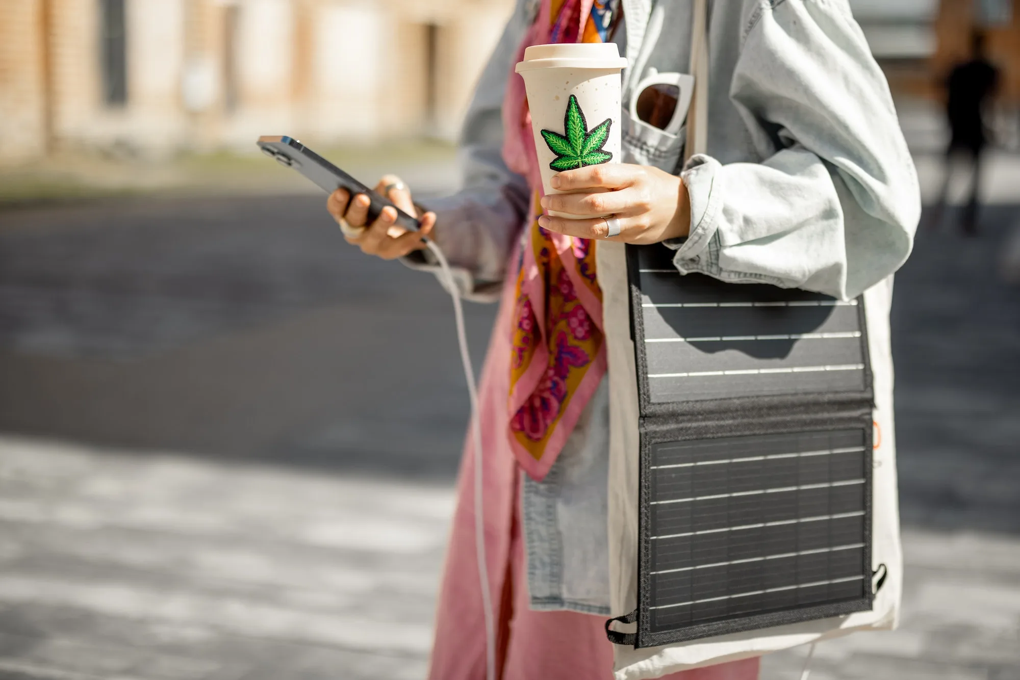 Woman charge phone from portable solar panel while walking outdoors